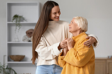 Young woman with her grandmother hugging at home © Pixel-Shot