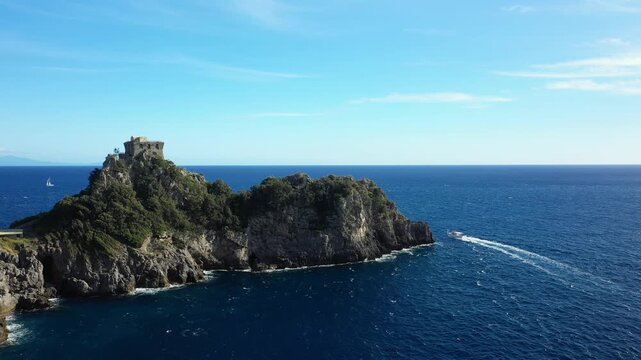 A scenic aerial view of Capo di Conca s rocky coastline and historic watchtower overlooking the blue Mediterranean Sea on a clear day.