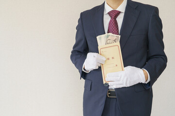 給料袋を持つスーツを着た男性｜日本の一万円札の入った給料袋