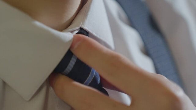 Student Adjusts Clothing Precisely. Student Meticulously Straightens His Shirt And Tie For Appearance. Student Diligently Ajusts His Uniform And Carefully Aligns His Tie Around His Collar