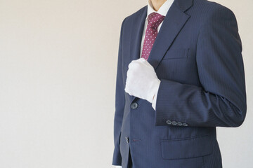 白い手袋で拳を握るスーツ姿の男性｜やる気イメージ