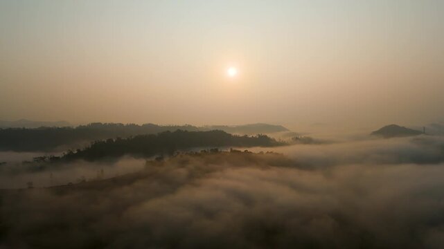 4K aerial view of a morning sunrise over dark mountain peaks, surrounded by a thick sea of fog and mist.
