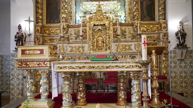 Gold carved altar with columns red carpet candles chairs and cross