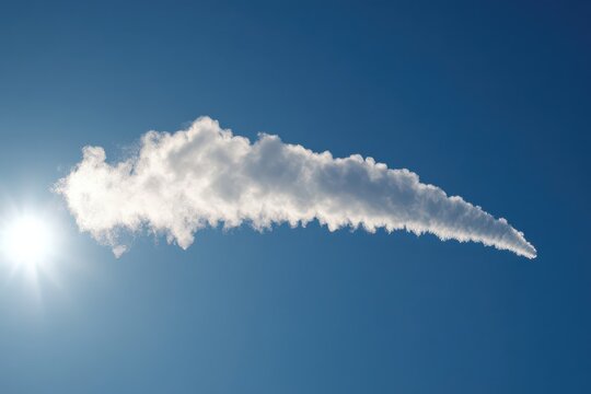Elongated cloud with icy edges in bright blue sky with sun