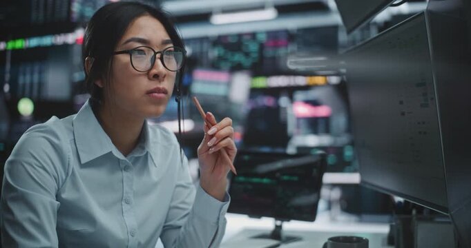 Asian Woman in Headset Intently Scrutinizes Vast Amounts of Financial Data and Intricate Graphs Displayed Across Multiple Screens. Concentration and Strategic Analysis in Digital Stock Exchange.