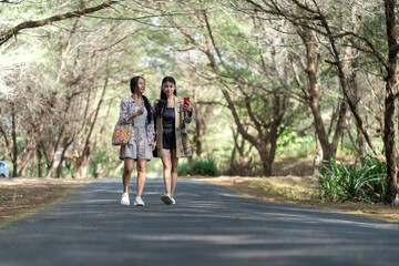 Obraz premium Asian Indonesian Women Friends Walking on Forest Road Taking Selfie