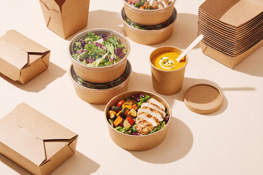 Healthy takeaway meal containers with salad bowl soup and eco kraft packaging arranged in modern studio food photography style