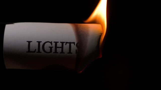 Slow motion close-up of the word LIGHTS burning on a black background