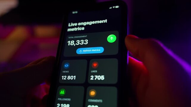 Blogger watching blog statistics on smartphone screen, close-up in dark room