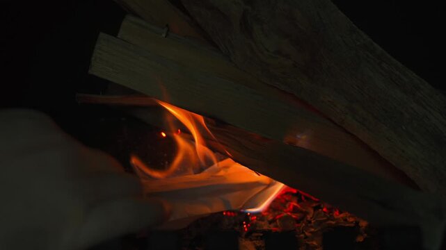 Lighting a fire in a fireplace with a sheet of paper, close-up