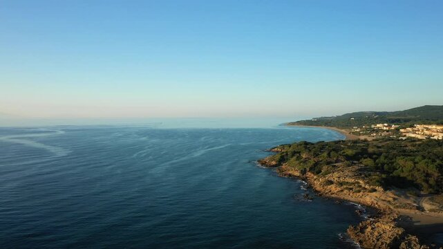 Scenic aerial view of the Arkoudi coastline with clear blue sea and lush greenery under a bright morning sky. The tranquil landscape highlights the natural beauty of this Greek coastal area.