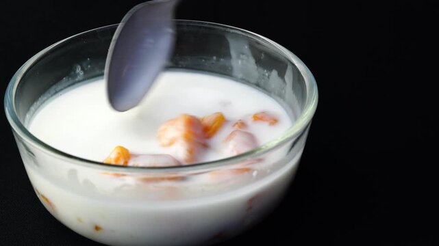 Ladling takioca balls in coconut milk in glass bowl. Tapioca balls in coconut milk is traditional dessert in Thailand.