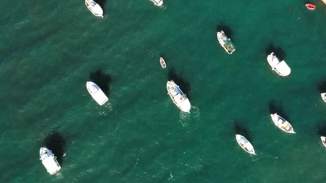 Drone shot of several boats floating on turquoise water in the harbor of Koroni, Greece, creating a tranquil maritime scene.