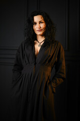 Naklejka premium Woman with dark hair stands indoors wearing a black outfit