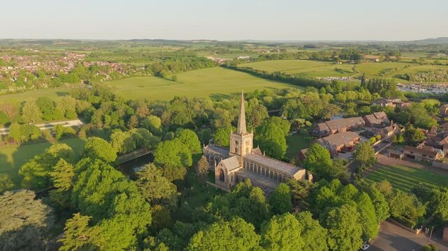 Drone orbiting shot of the Gothic Holy Trinity Church, capturing the sparkling River Avon and the lush, blooming spring nature surrounding Shakespeare&rsquo;s church in Stratford-upon-Avon.
