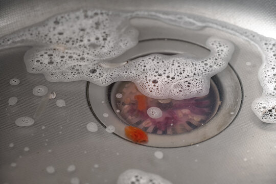 Close-up of a clogged kitchen sink with food and food debris.