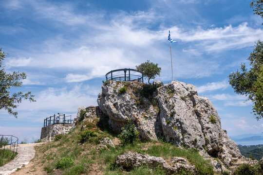Kaisers Throne viewpoint above Pelekas village on Corfu island, Greece. Metal deck and Greek flag on rock, stone path