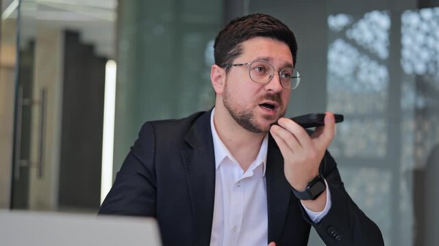 Professional records voice message with smartphone in contemporary office. Exhibits focus, professionalism, and confident communication, conveying important information.
