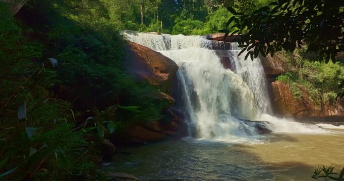 Beautiful rainy season aerial shot of Tat Huang Waterfall in Loei Province. Positioned between Thailand and Laos, this international waterfall is framed by tropical forest, peaceful mountains