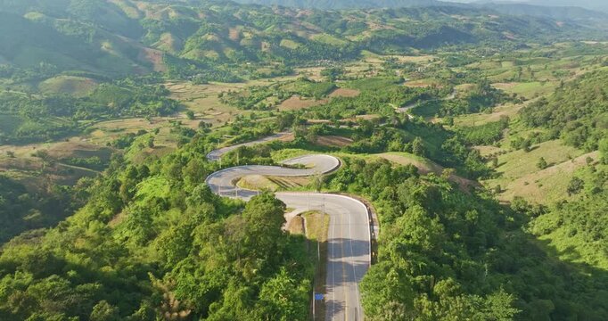 A panoramic aerial landscape of endless curves along a mountain road, blending seamlessly with lush forests and serene high altitude surroundings.