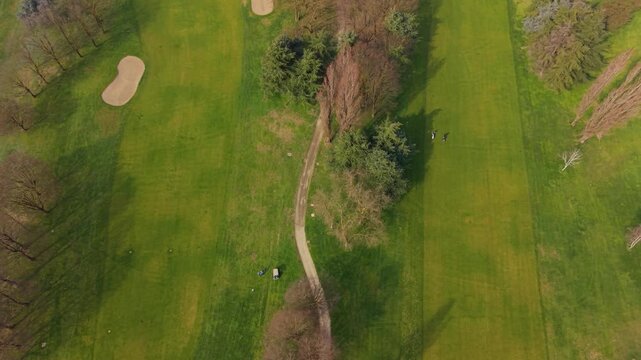 Scenic Golf Course: Aerial view of a golf course featuring lush green fairways, sand traps, and surrounding trees. 