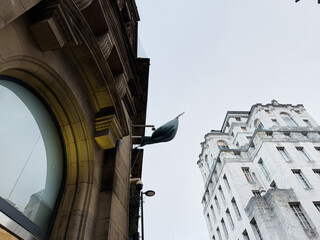Naklejka premium Flag on a grand stone storefront in Manchester UK showcasing architectural contrast