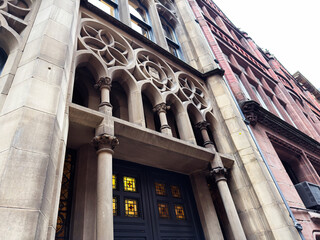 Naklejka premium Historic architecture facade with arches and columns in Manchester, UK, featuring stonework and stained glass