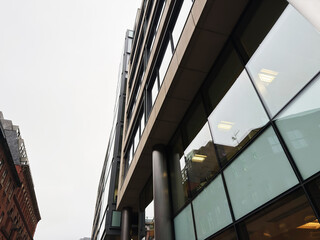 Naklejka premium Modern glass facade of Manchester office building captured from street level with dramatic perspective