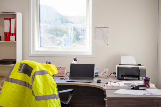 Workstation set up with a laptop and documents in an office during daylight hours