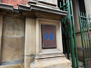 Naklejka premium House number 46 plaque on stone column at Manchester building beside a green iron fence