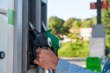 Filling fuel at gas station with a green and black pump during daylight hours © Iryna