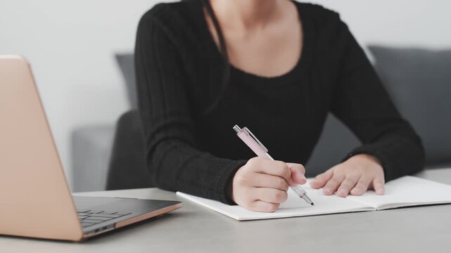 デスクでノートパソコンを見ながら勉強する女性