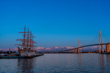 夕方の海王丸パークから新湊大橋と海王丸を前景にピンク色染まる立山連峰アーベンロート