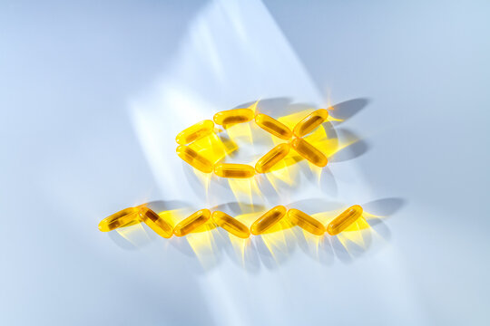 Fish oil softgel capsules arranged in the shape of a fish and water waves, symbolizing essential omega 3 fatty acids and nutritional supplements for a healthy heart and overall wellness