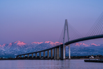 夕方の海王丸パークから新湊大橋と海王丸を前景にピンク色染まる立山連峰アーベンロート