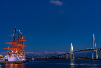 夕方の海王丸パークから新湊大橋と海王丸を前景にピンク色染まる立山連峰アーベンロート