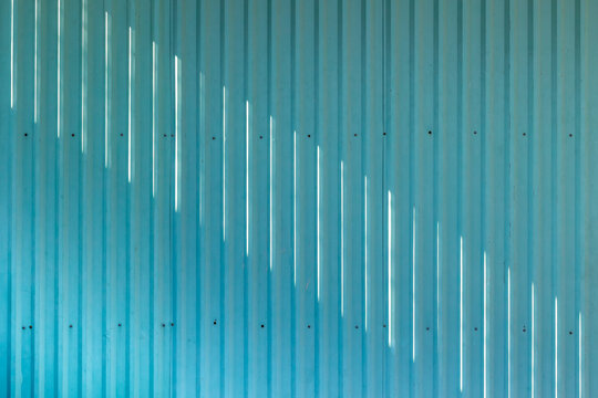 Corrugated metal panels with slotted light on teal wall