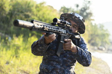 Obraz premium Focused soldier in camouflage aiming tactical rifle during military combat mission outdoor. special force operative with weapon showing concentration and precision