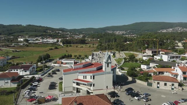 Drone aerial view of Igreja Paroquial de Lij&oacute; in Barcelos Portugal showing modern parish church cemetery village houses farmland and green hills in Minho region
