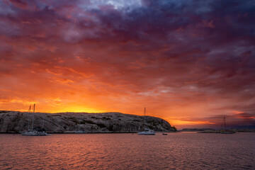 Colorful sunset above sailboats anchored in bay facing Gluppö in Fjällbacka archipelago, Bohuslän, Sweden © TasfotoNL