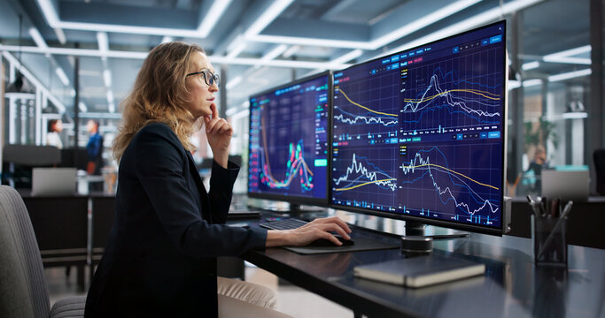 Female Broker Analyzing Data On Multiple Screens