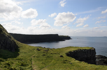 Scenic coastal landscape with high cliffs and blue ocean under cloudy sky