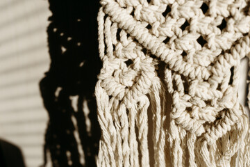 Macrame textile detail in warm sunlight with strong shadows. Boho interior decor texture for minimalist home styling.  © ShvedKristina