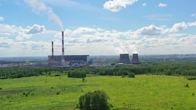 A coal power plant with smoke stacks at dusk with a blue sky. Thermal power station. Lignite power plant producing electrical energy.  Electricity production or water heating facility with fission met