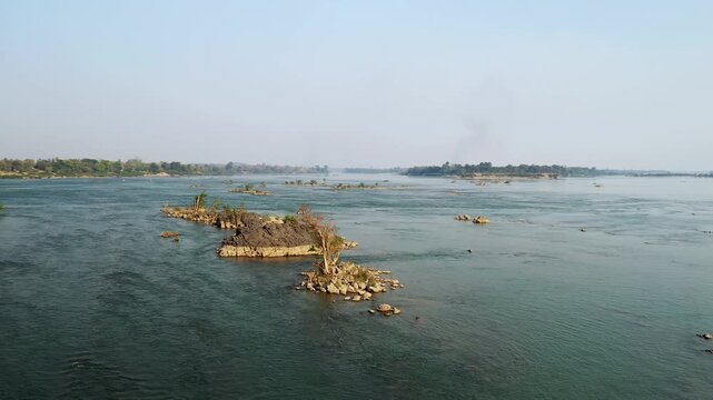 Aerial view of small rocky islands scattered across the Mekong River at Si Phan Don, also known as the 4000 Islands region in Laos. Tranquil natural landscape under clear sky.