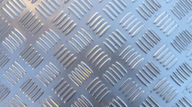 Video of aluminum checker plate metal texture with diagonal raised pattern industrial background.