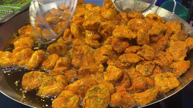 Video of Thai fish cake frying in large pan with hot oil at vibrant street food stall.