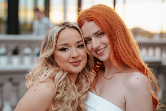 Two Sisters in Prom Dresses, Embracing, Sunset Background