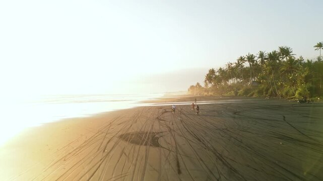 Aerial view of local people racing on motorcycles on a tropical beach in Bali during sunset
