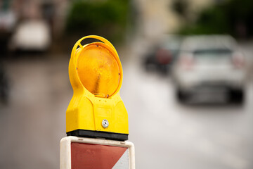 Bright Yellow Warning Light on Road Barrier at Construction Site, Guiding Traffic Safely Through Urban Development and Maintenance Work